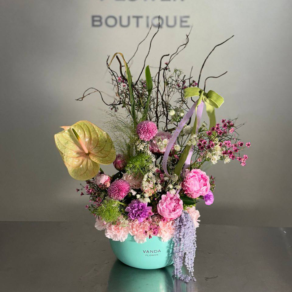 Luxury pink garden style fresh flower arrangement in a round flower box with soft pastel blooms