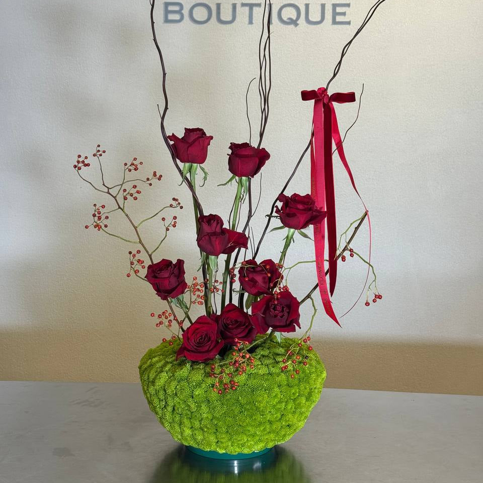 Elegant small red rose arrangement with green base, berries and red ribbon – Vanda Flower Boutique