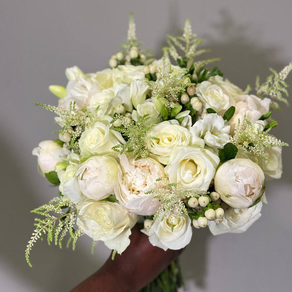 White bridal bouquet with peonies, roses, lisianthus and hypericum berries.