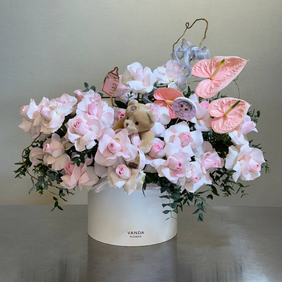 Pink newborn flower arrangement with roses and anthuriums in a white vase